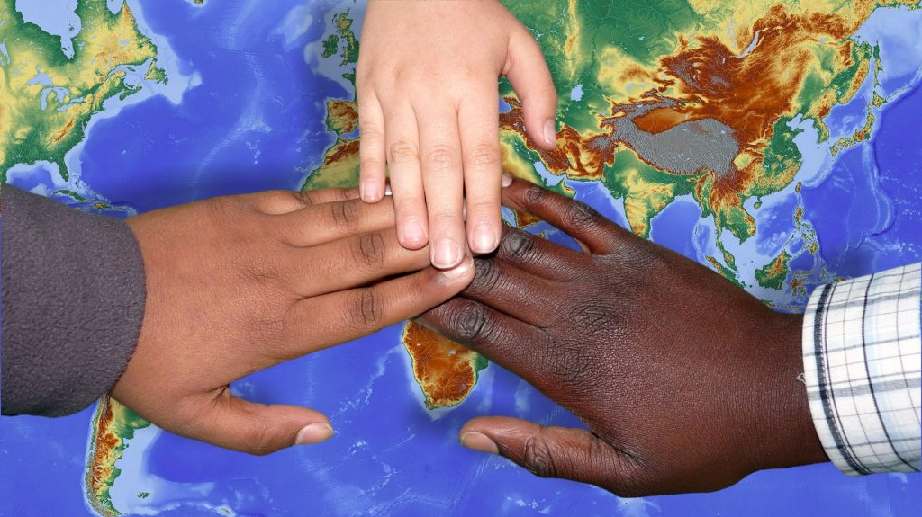 Hands of many colors on the world